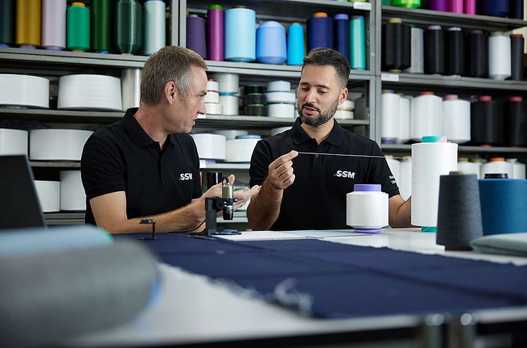 Textile technologists discussing yarn assessment results to ensure quality and performance standards.