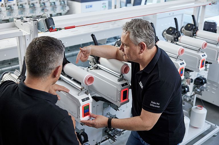 SSM textile technologist explaining the details of an assembly winding machine to a customer during a training session.