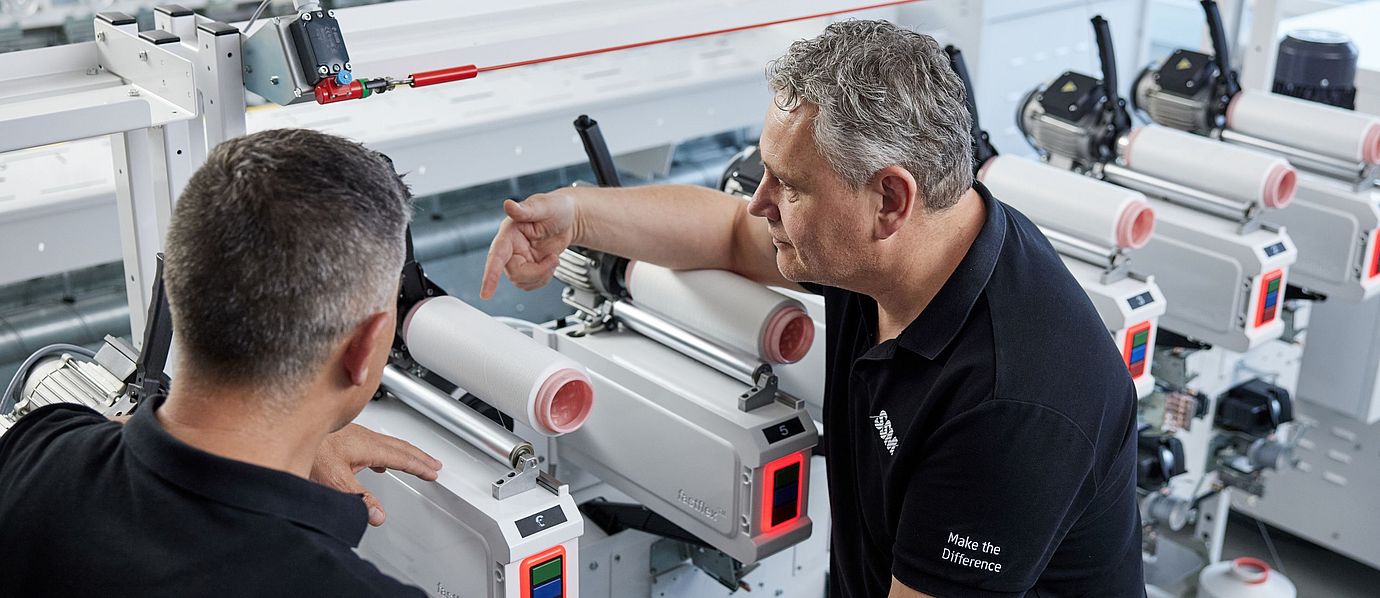SSM textile technologist explaining the details of an assembly winding machine to a customer during a training session.